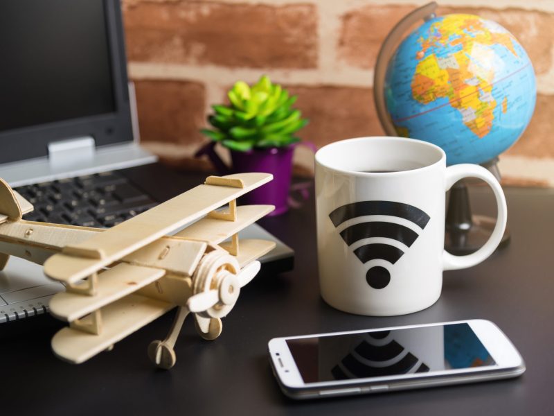 Table of office stuff Business man with Laptop, Wireless mouse, Smart phone, Toy wooden plane and Coffee Cup WIFI symbol.Concept office Business man workplace.