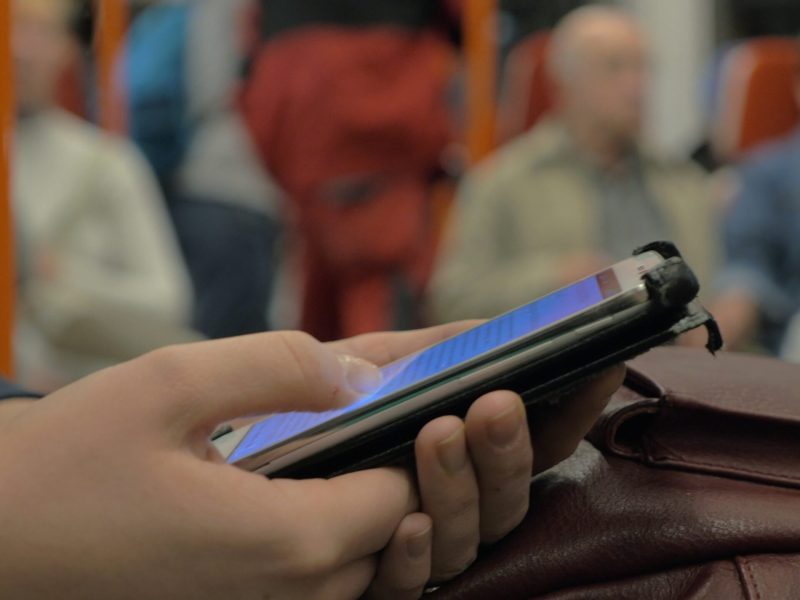 Close-up shot of a woman commuter browsing web on smart phone during ride in subway train